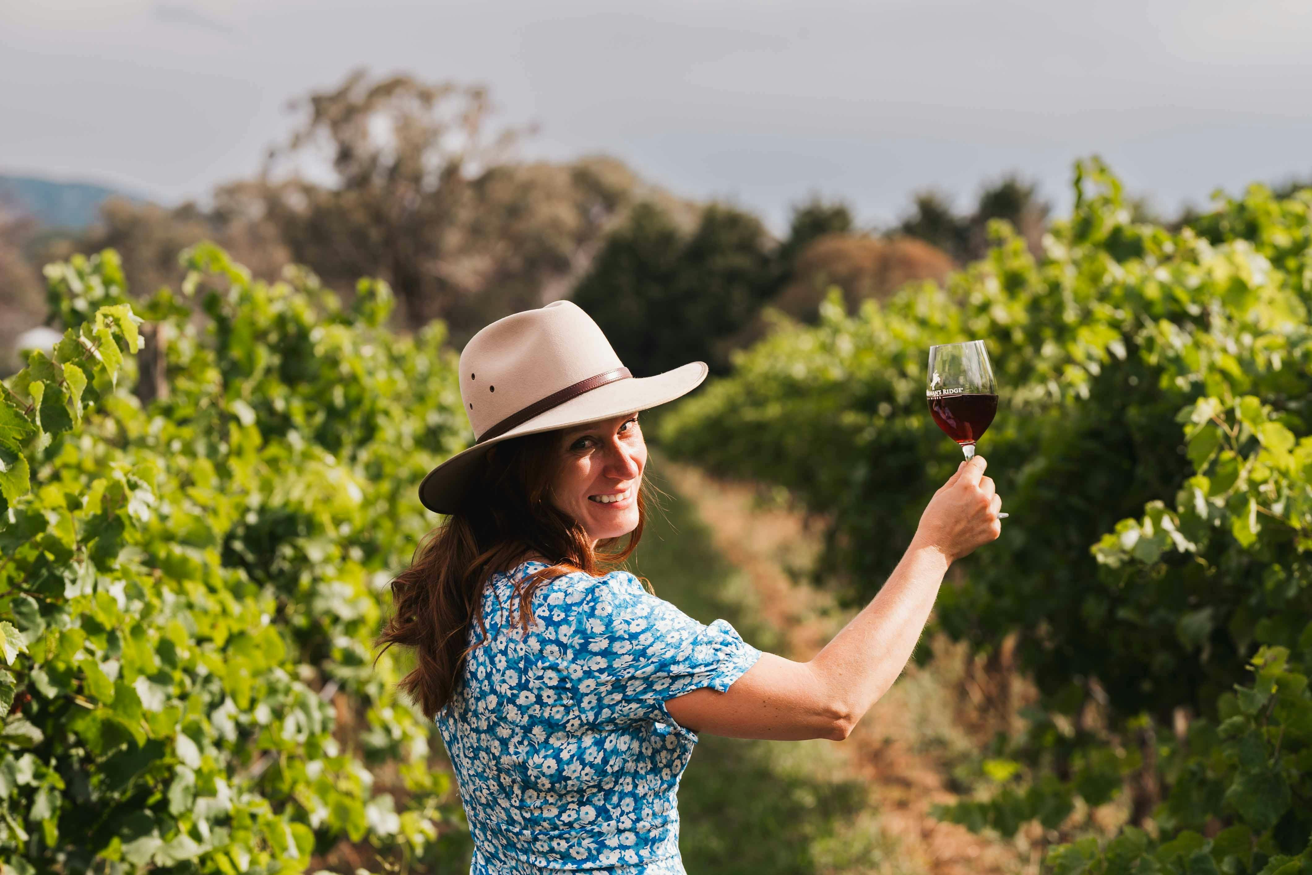 girl holding red wine in front of vineyard at Stockmans Ridge Wines