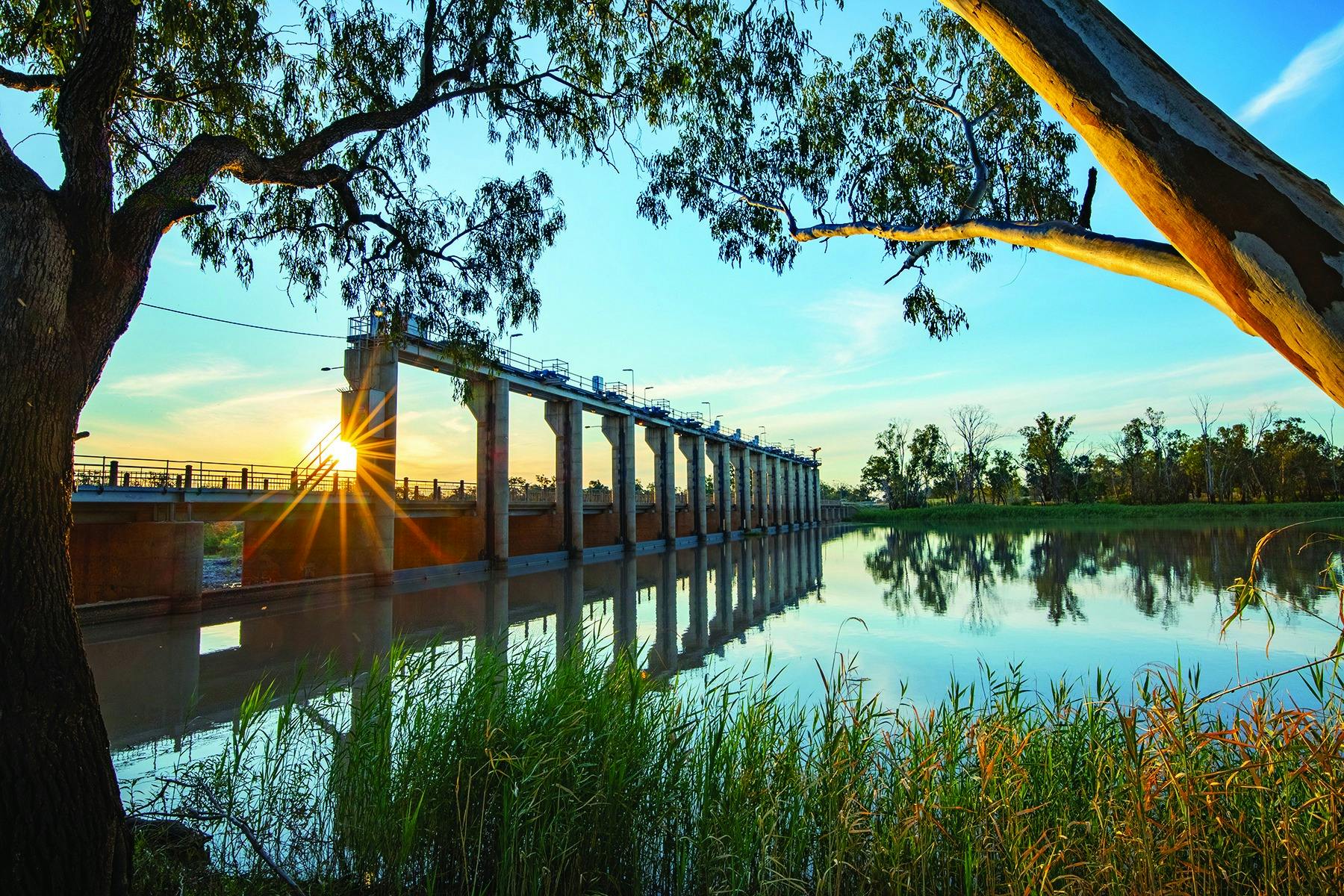 Large man made concrete weir reflecting in river below