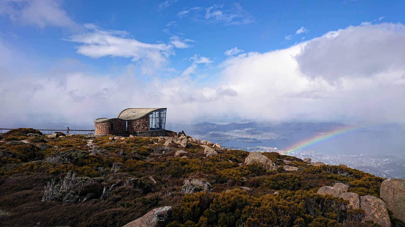 The summit of kunanyi/Mt Wellington with a rainbow over Hobart