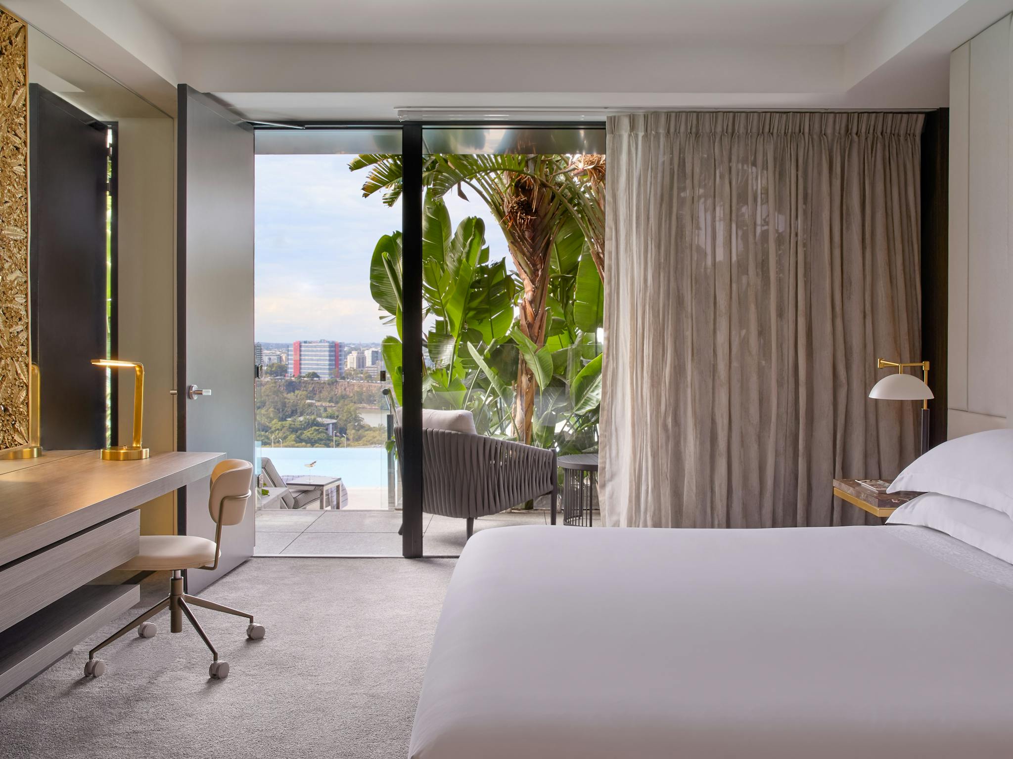 Bright hotel room leading to a terrace with tropical plants and an infinity pool outlook Bright hotel room leading to a terrace with tropical plants and an infinity pool outlook