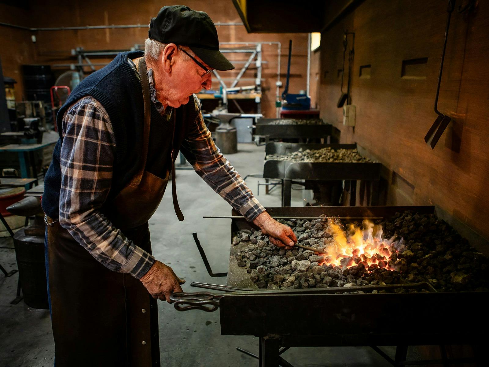 Blacksmith working coals to heat metal at Cobb+Co.