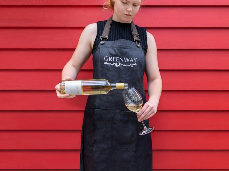 A Greenway Wines team member is pouring a glass of delicate pinot grigio