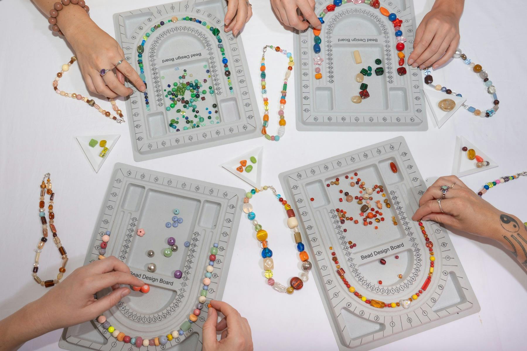 3 women making necklaces at a table.