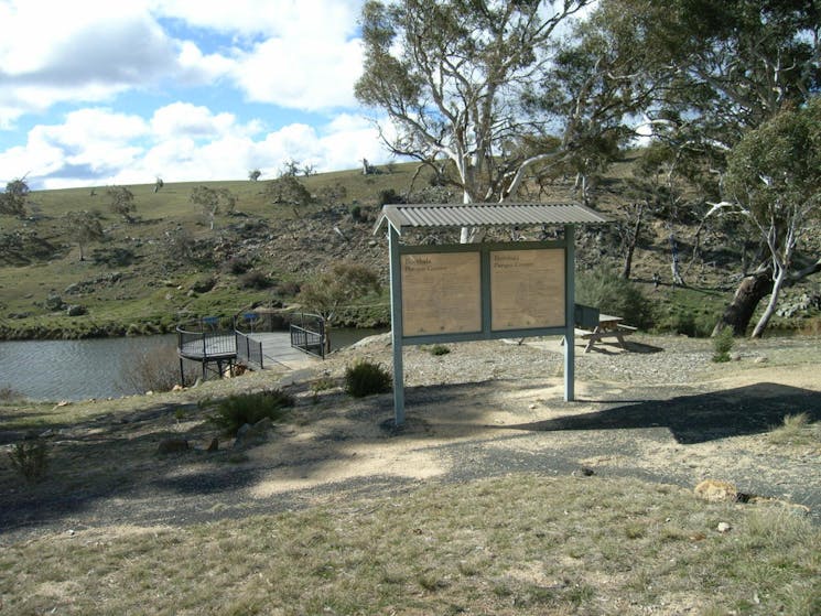 Sign with viewing platform over water body and hill in background