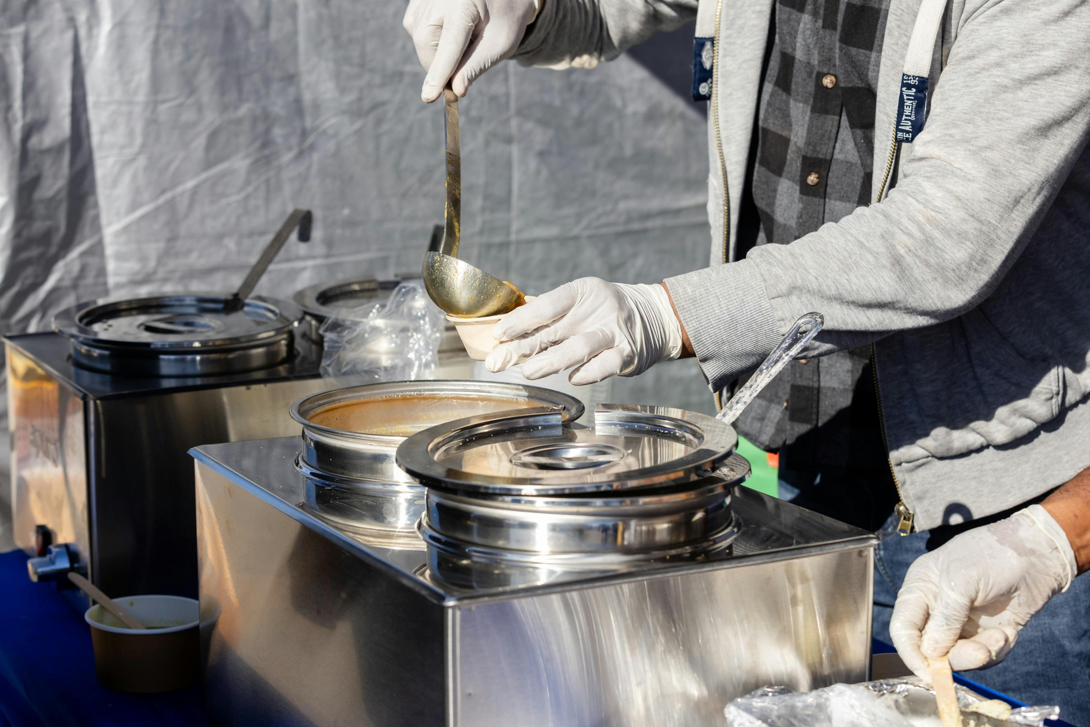 Image of hands ladling soup into a takeaway cup
