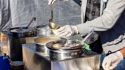Image of hands ladling soup into a takeaway cup