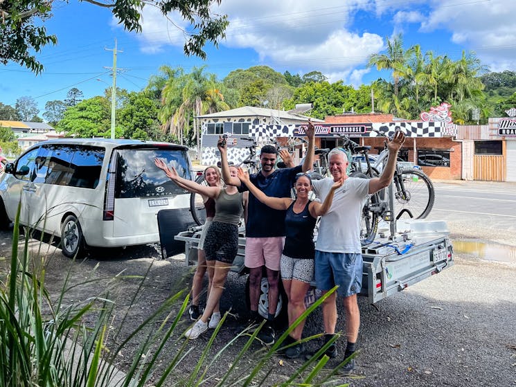 Shot of a group of riders standing next to trailer with hands in air after finishing an e bike tour