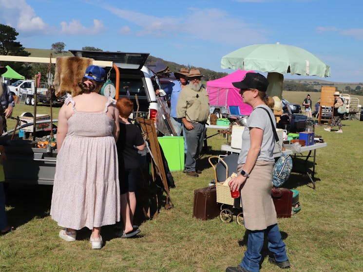 Rear view of one woman and another in profile viewing merchandise on a row of stalls