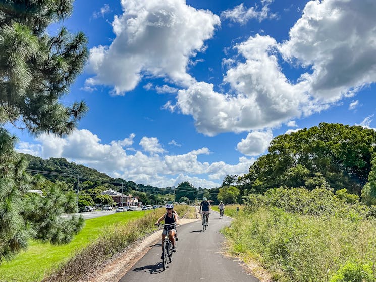 Front shot of e bike riders approaching under blue sky on Northern Rivers Rail Trail in Mooball.