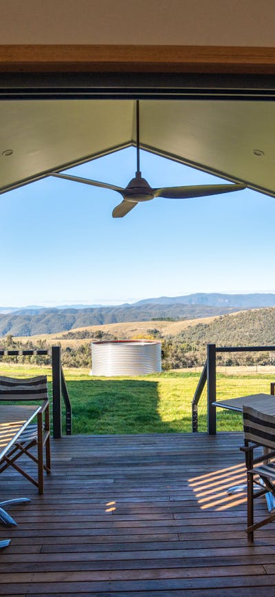 Outdoor deck area with seating overlooking expansive countryside and mountain views.