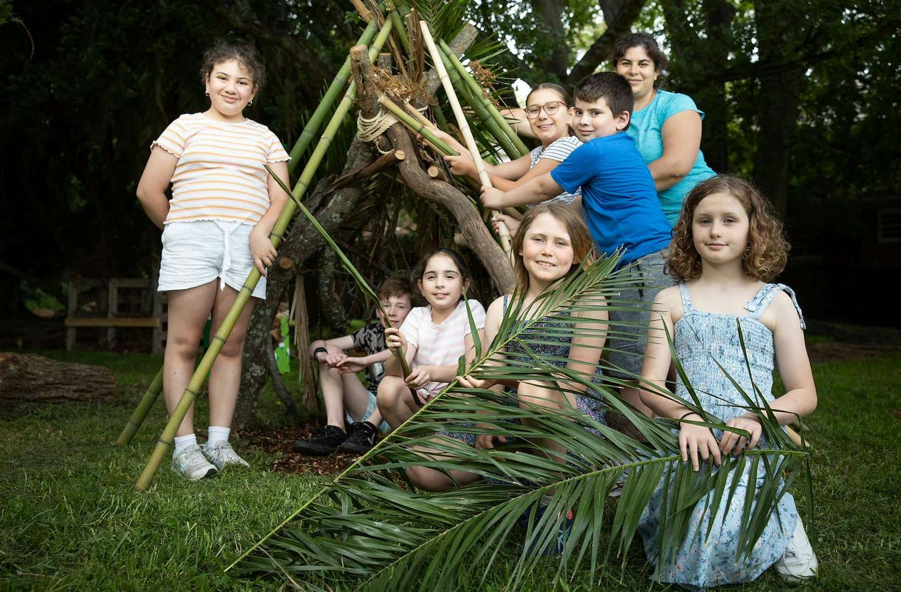 Children standing with a stick shelter outdoors