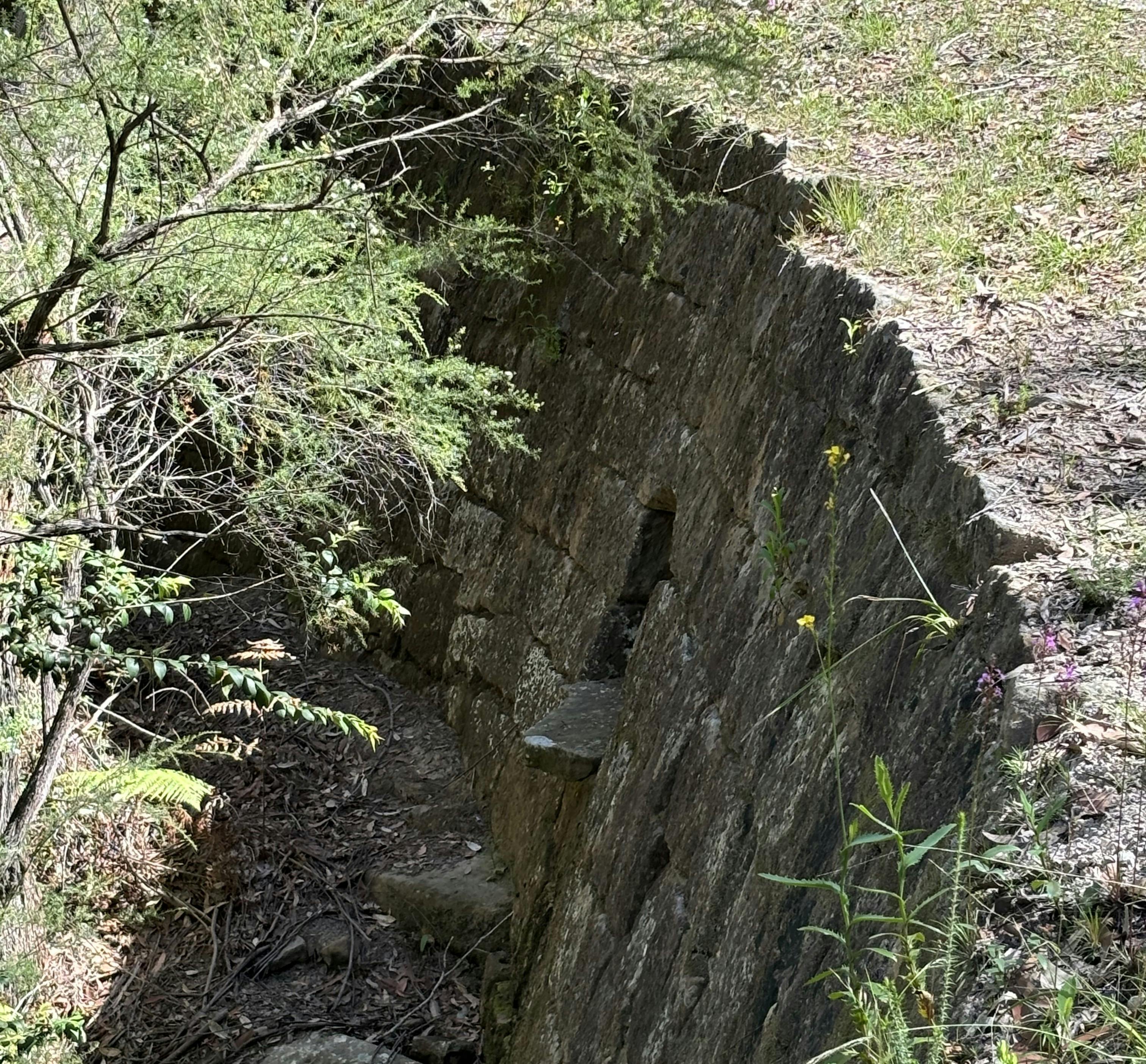 A large dry stone wall supporting the edge of a an old convict road.