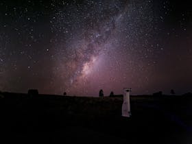 The Milky Way is rising in the background with a telescope in the foreground