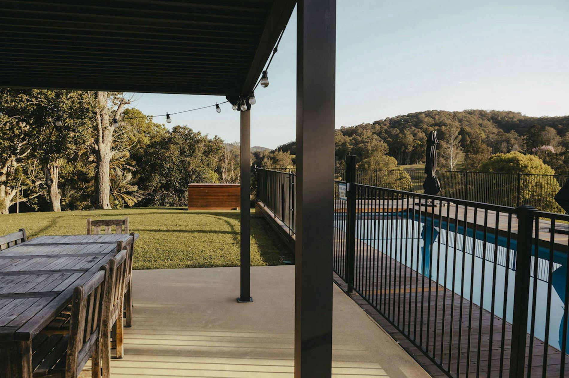 Outdoor Alfresco Area & Pool with green grass paddock and mountains with trees