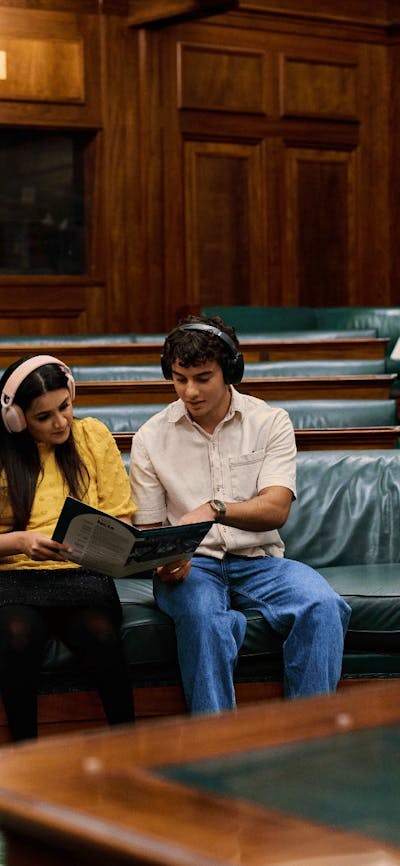 Two people seated in the House of Representatives listening to an audio guide