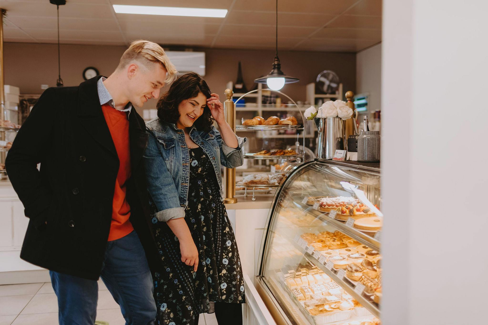 A couple standing in line at the Artisan Baker, deciding which pastry to select.