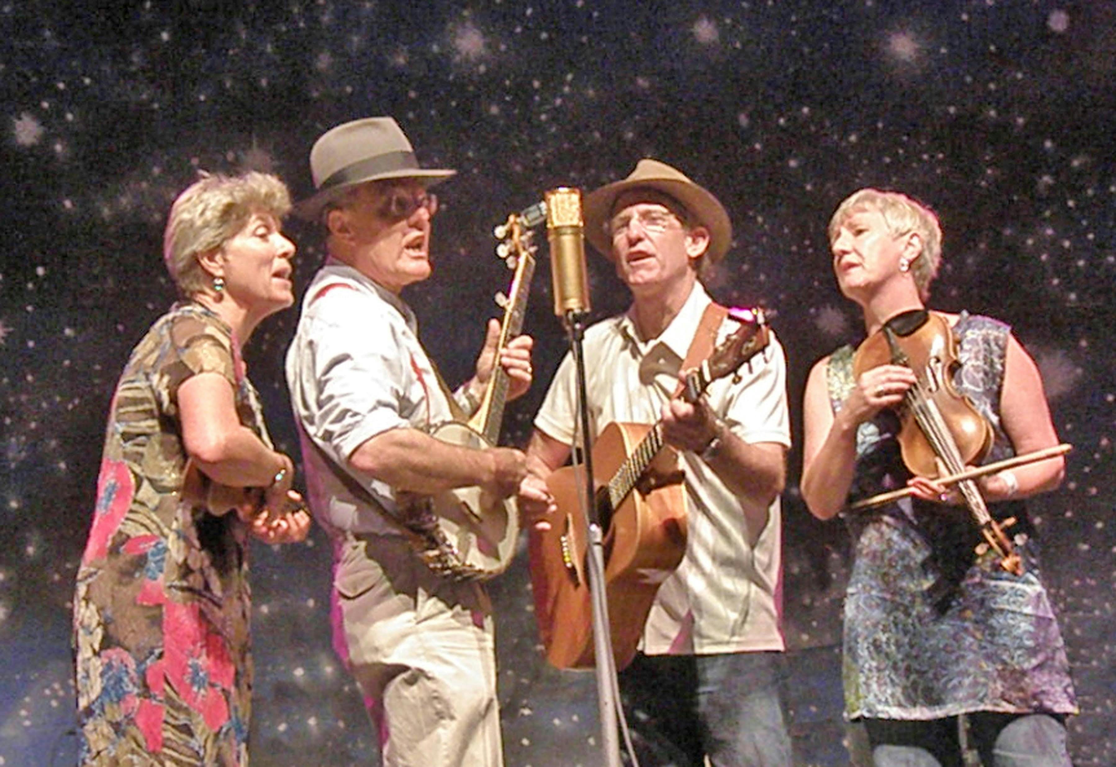 A group of people playing instruments and singing into a microphone on stage