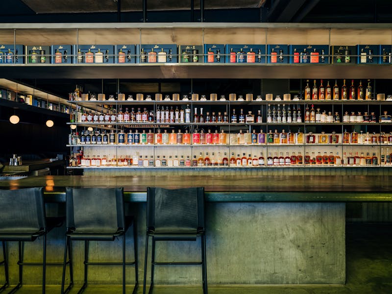 chairs at a bar with shelves stocked with whisky bottles