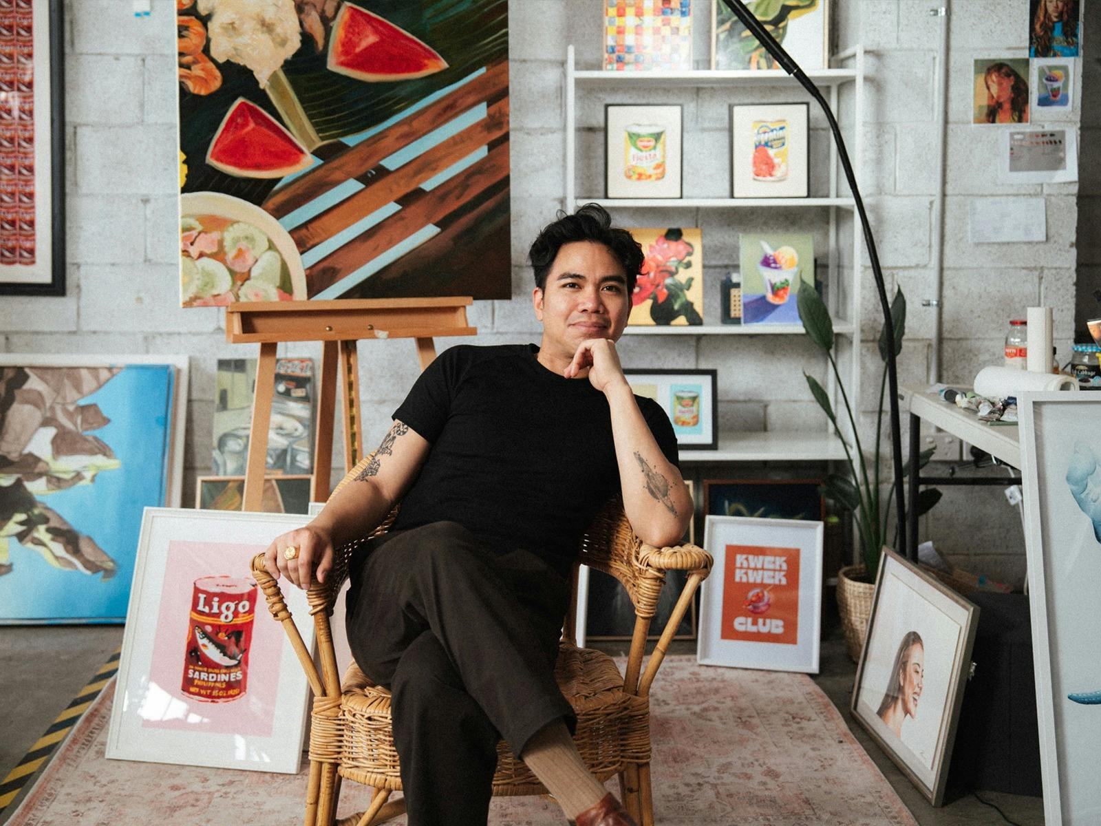 Artist Peter Francisco posing on a chair in front of his artworks