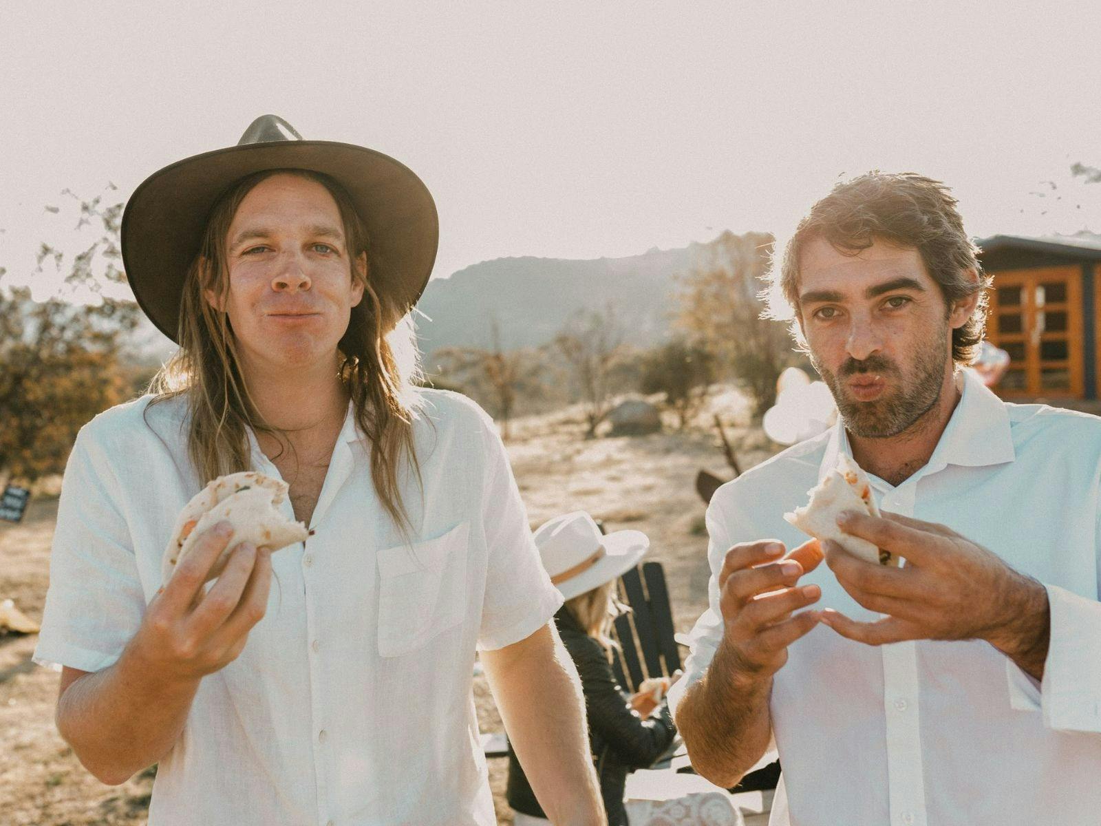 屋外のビール醸造所のビアガーデンでタコスを食べている男性2人