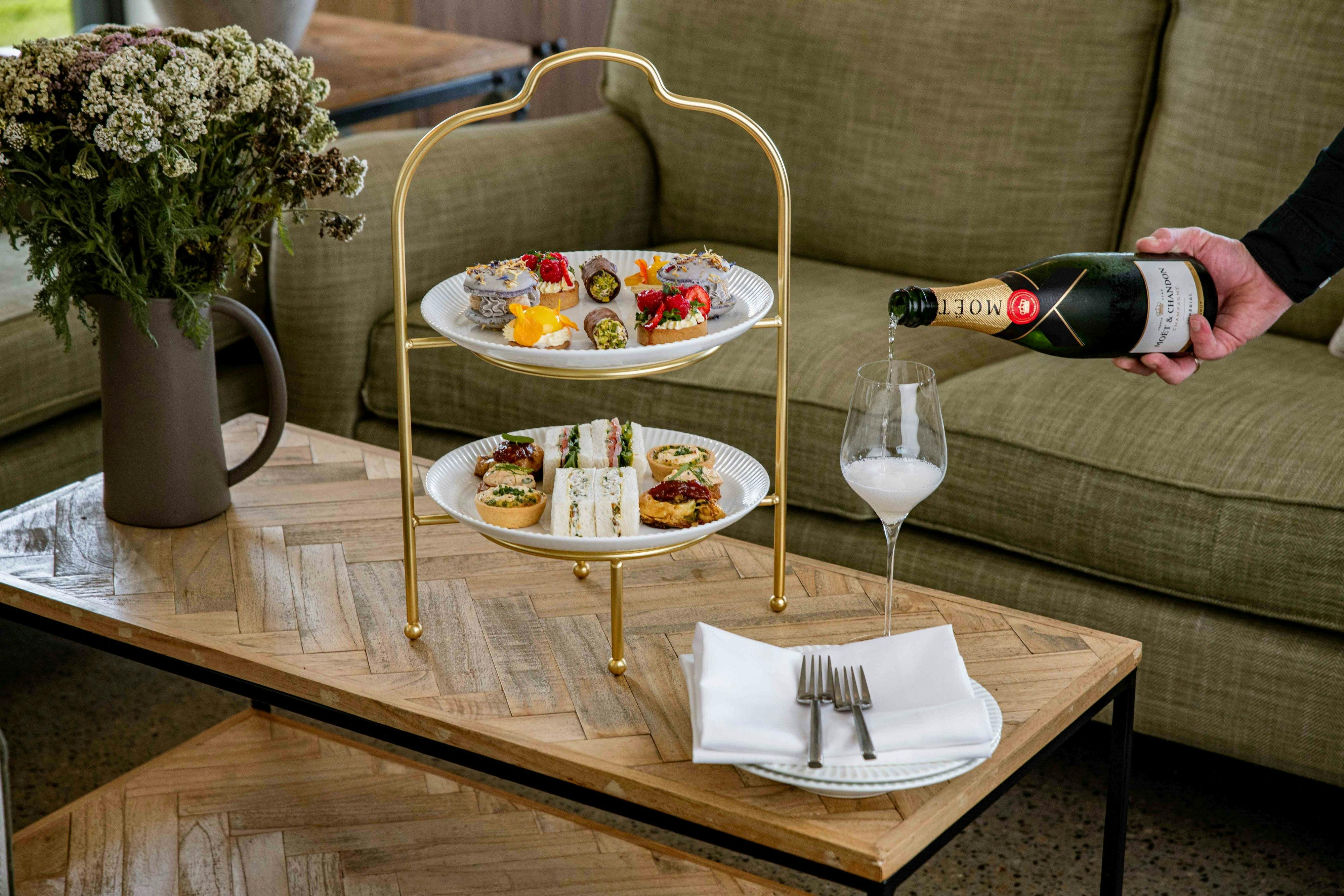Image of Champagne being poured at a table with high tea stand