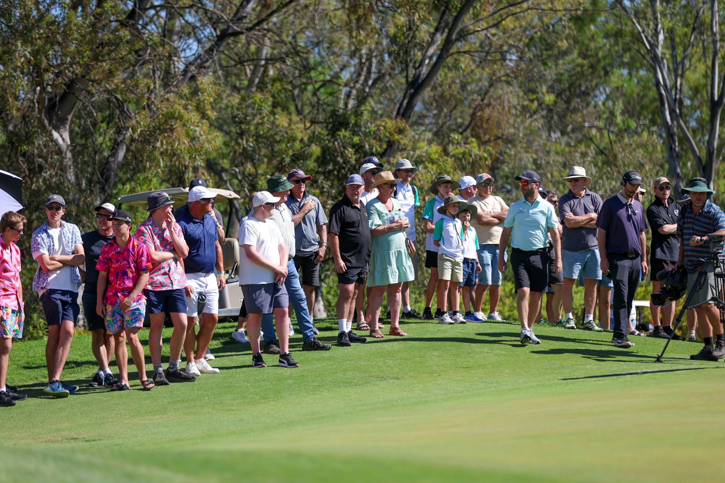 Spectators watching golf next to the putting green