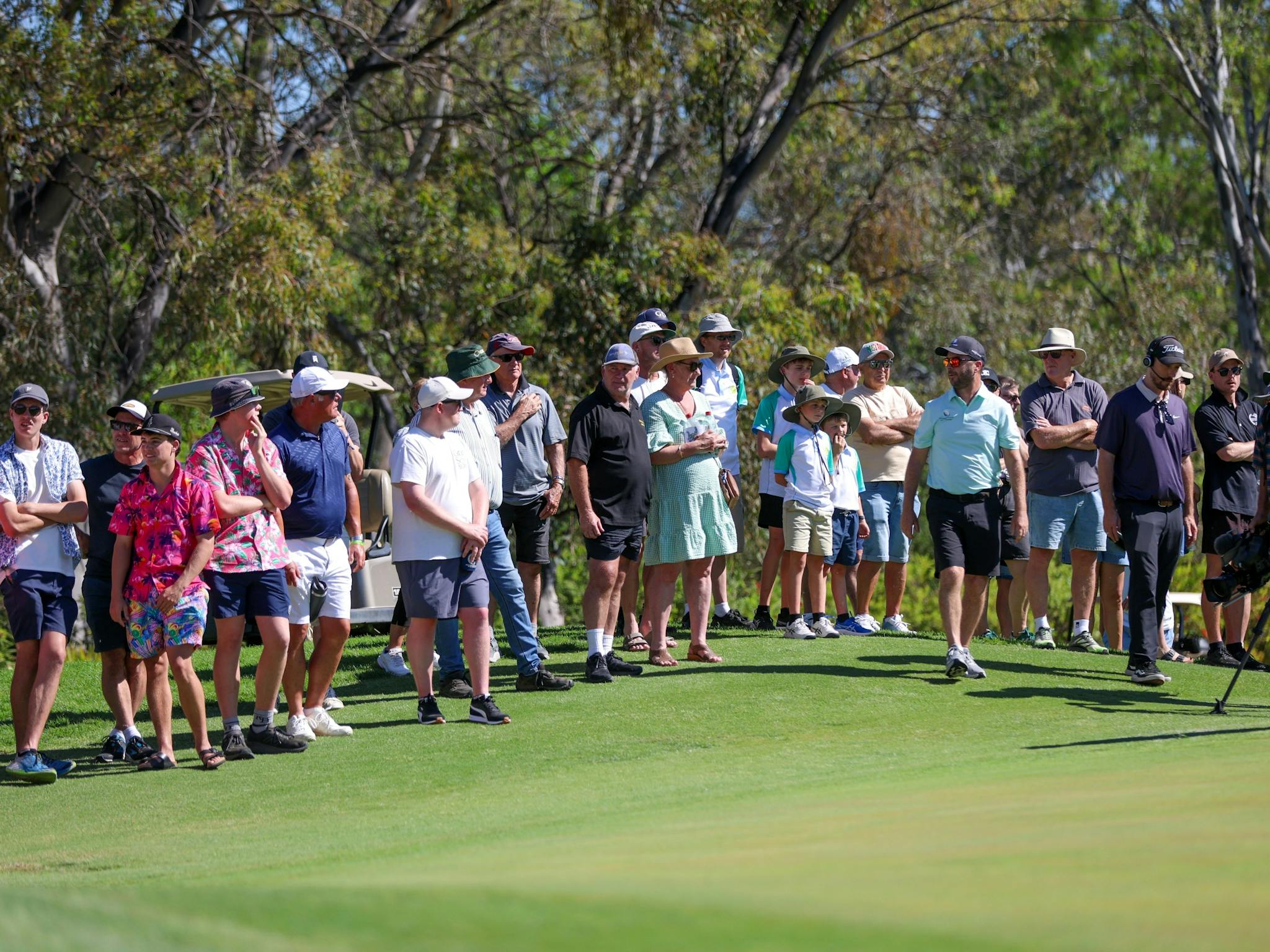 Spectators watching golf next to the putting green