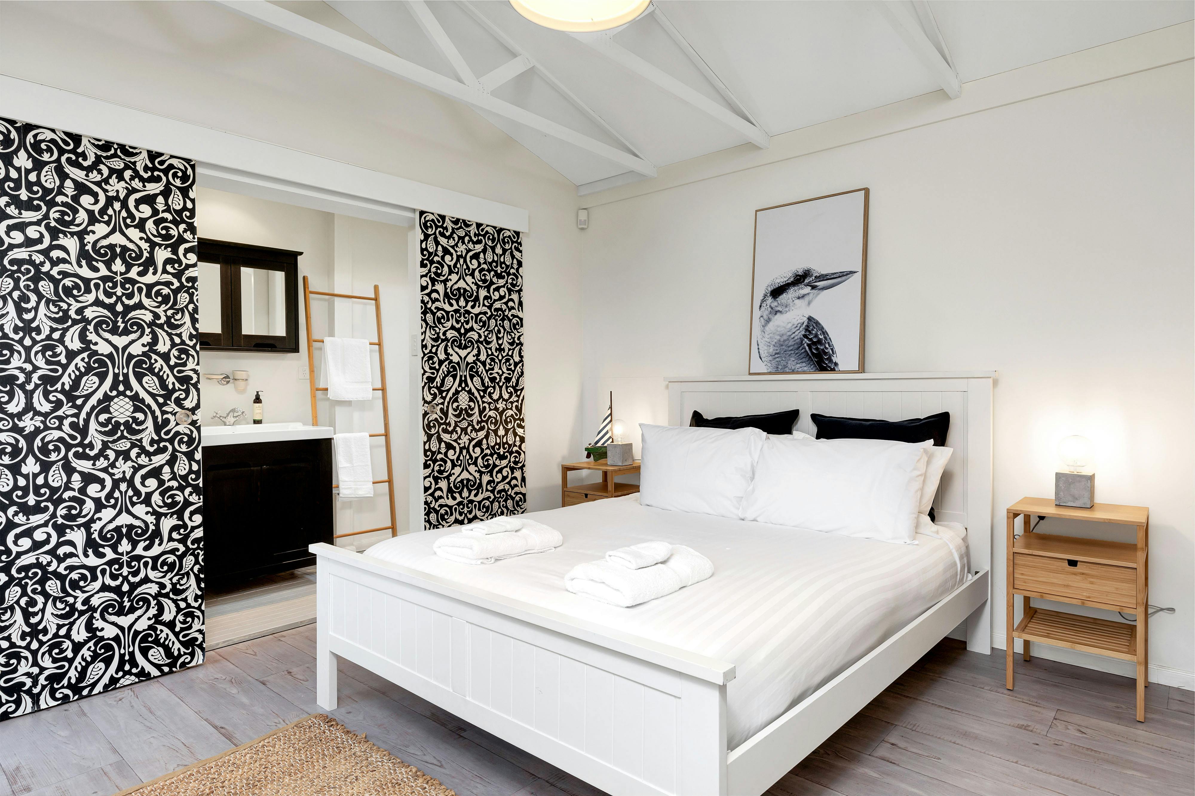 Queen bed with picture of framed kookaburra and entrance to bathroom separated by stable doors