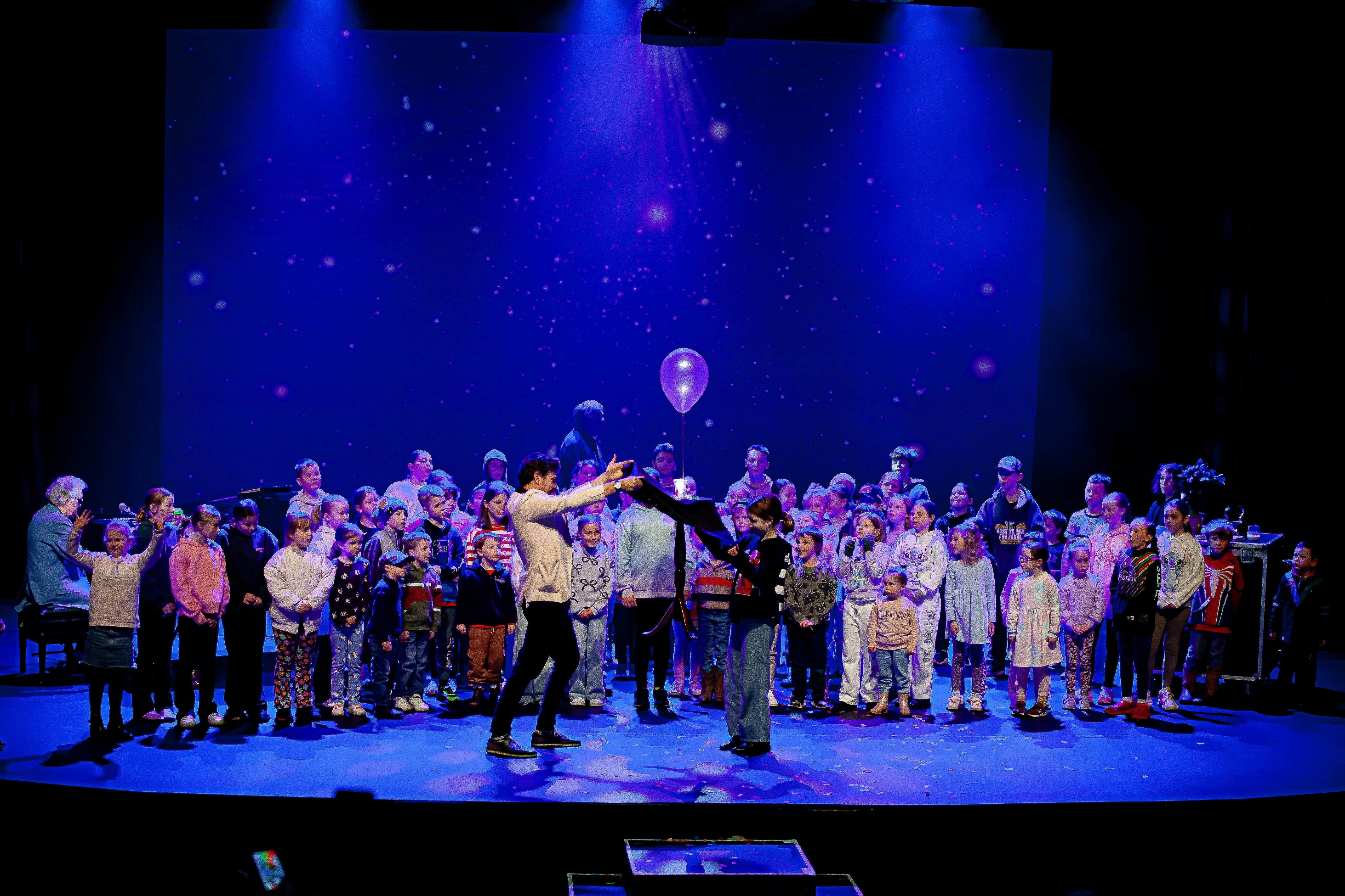 Adam Mada on stage with all the kids from the Audience