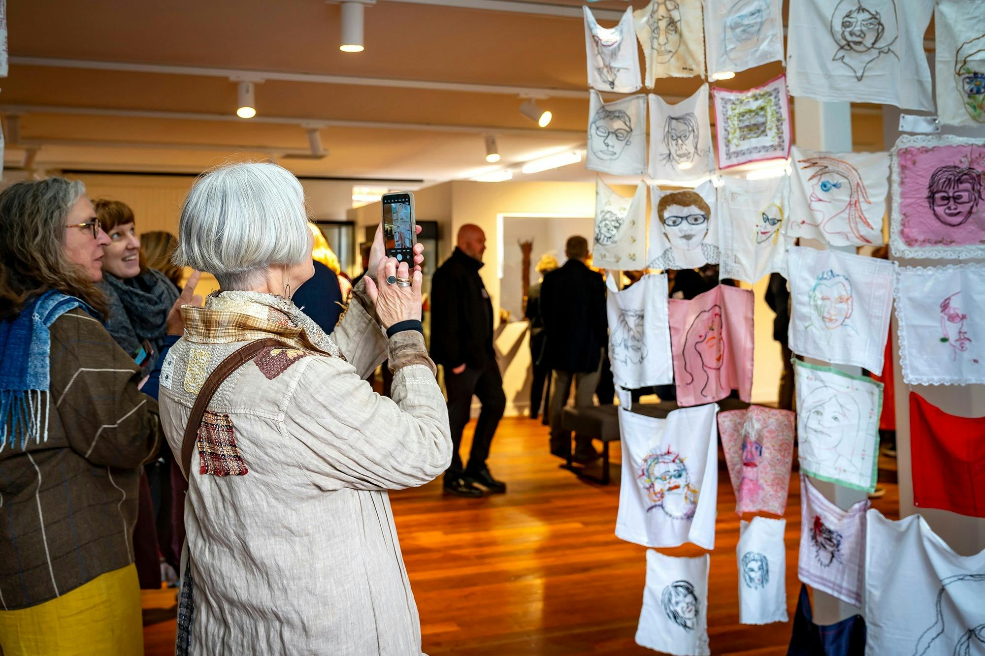 Person in image taking a photo of exhibition art work