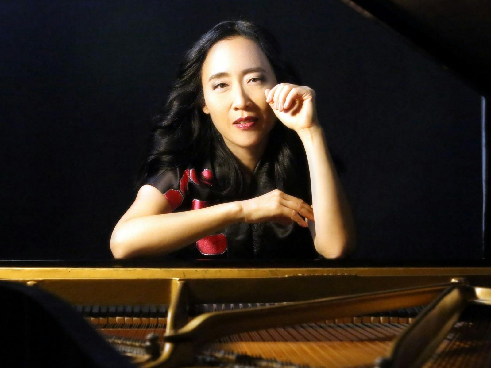 Picture of Helen Sung leaning on a grand piano looking through the lid