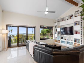 bright, modern living room with a large black leather sofa facing a built-in entertainment unit