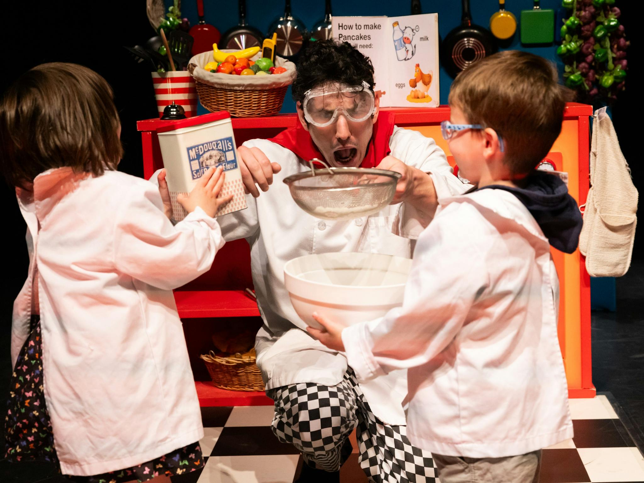 A person in goggles, holding a sieve over a mixing bowl, looks surprised in a playful kitchen scene A person in goggles, holding a sieve over a mixing bowl, looks surprised in a playful kitchen scene