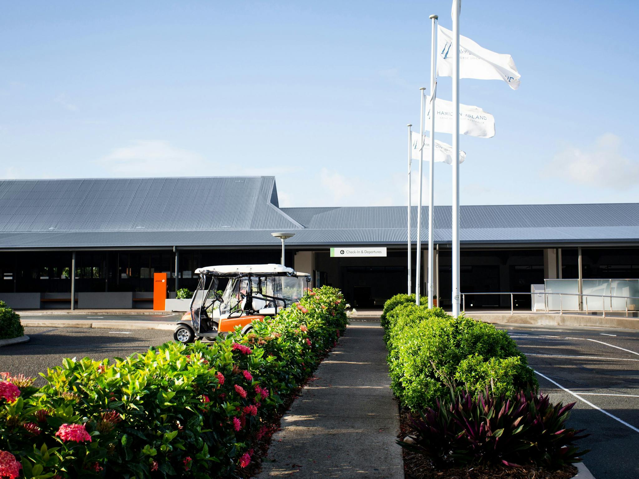 outside view to a small airport building with green bushes along the footpath outside view to a small airport building with green bushes along the footpath