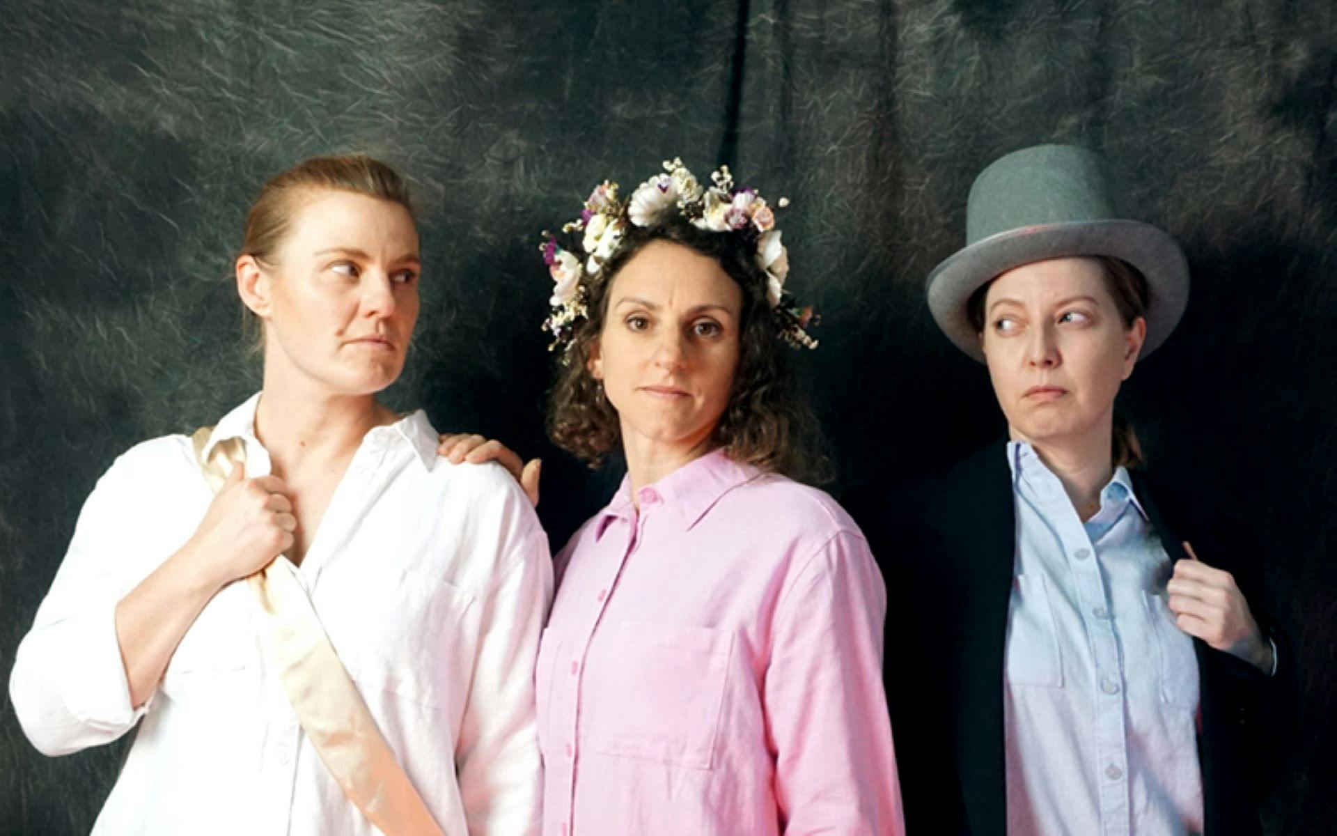 Three female-presenting performers, dressed in Regency-era casual clothing, gaze appraisingly.