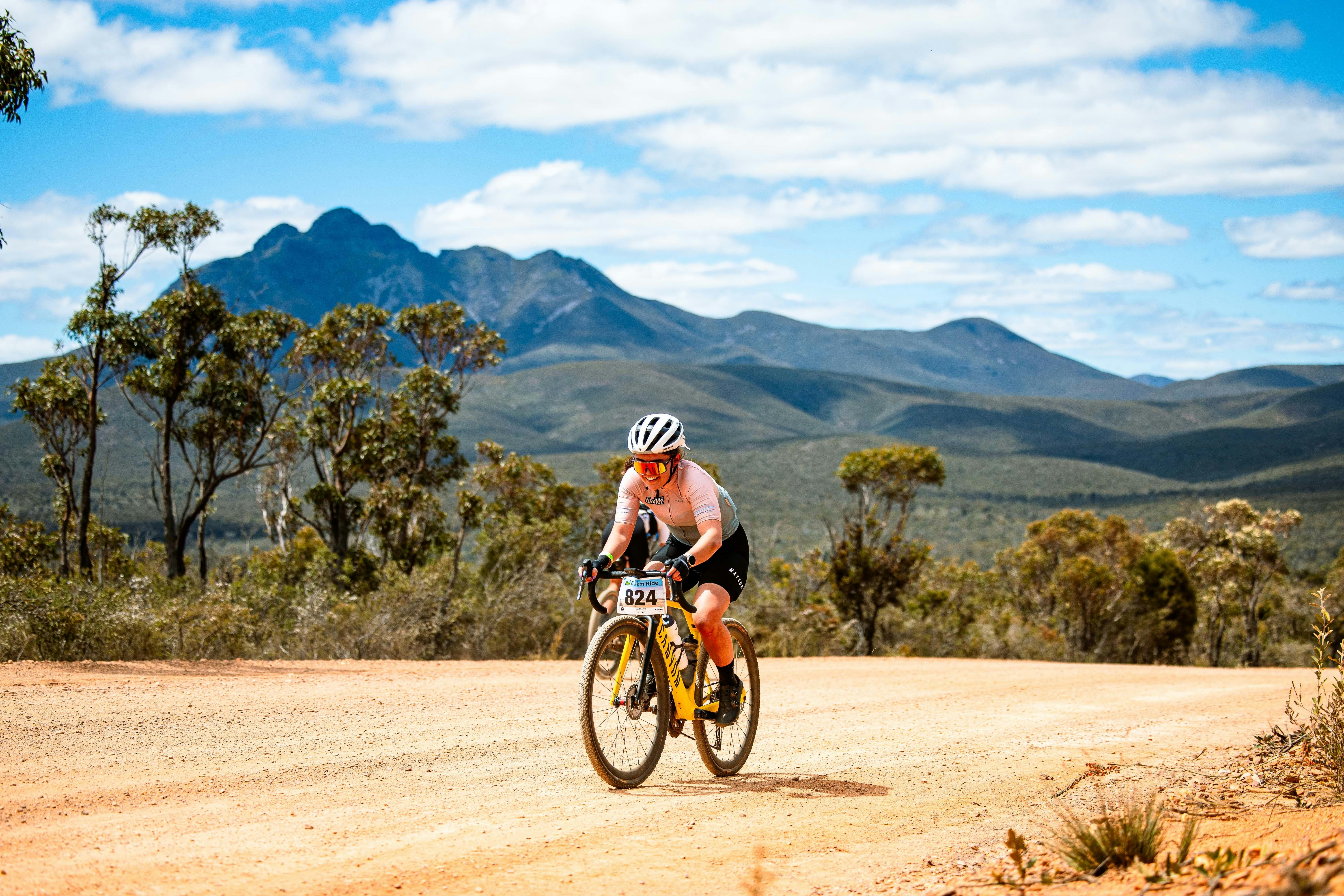 Ambassador Darcie Richards riding on gravel road with mountain backdrop