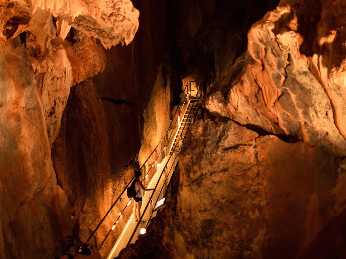 A woman walks across a metal walkway on a guided tour inside Chillagoe Caves in tropical north qld.