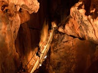 A woman walks across a metal walkway on a guided tour inside Chillagoe Caves in tropical north qld.