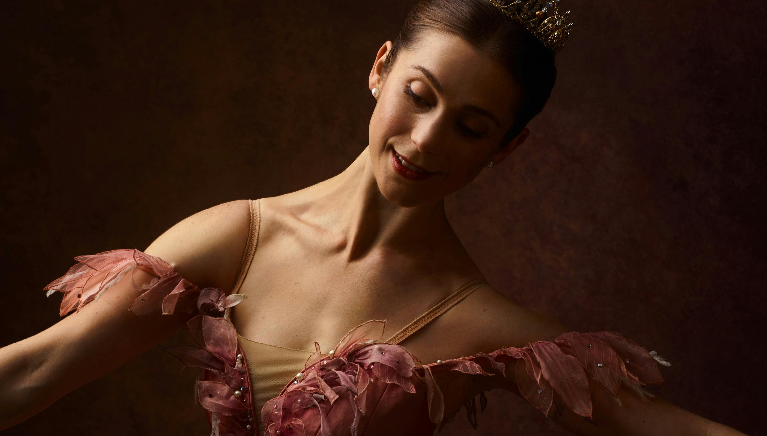 A dancer in a pink tutu looking down at the camera