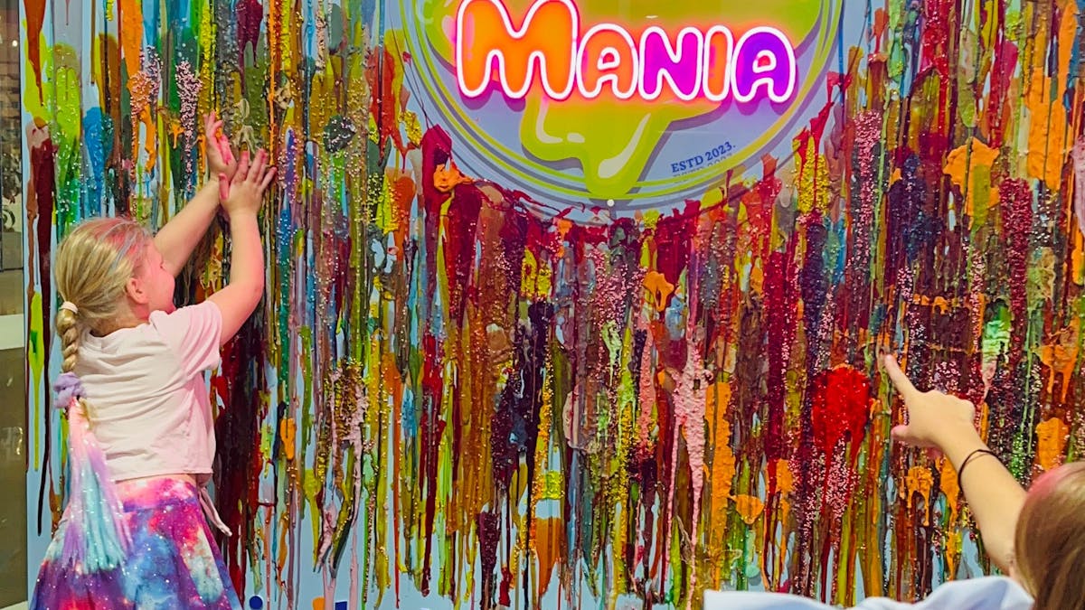 Slime wall where we have a Slime Mania logo and there is a girl sticking her favourite slime.