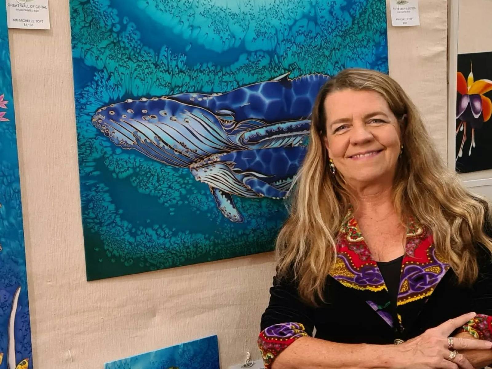 Kim Toft standing in front of her artwork of whales