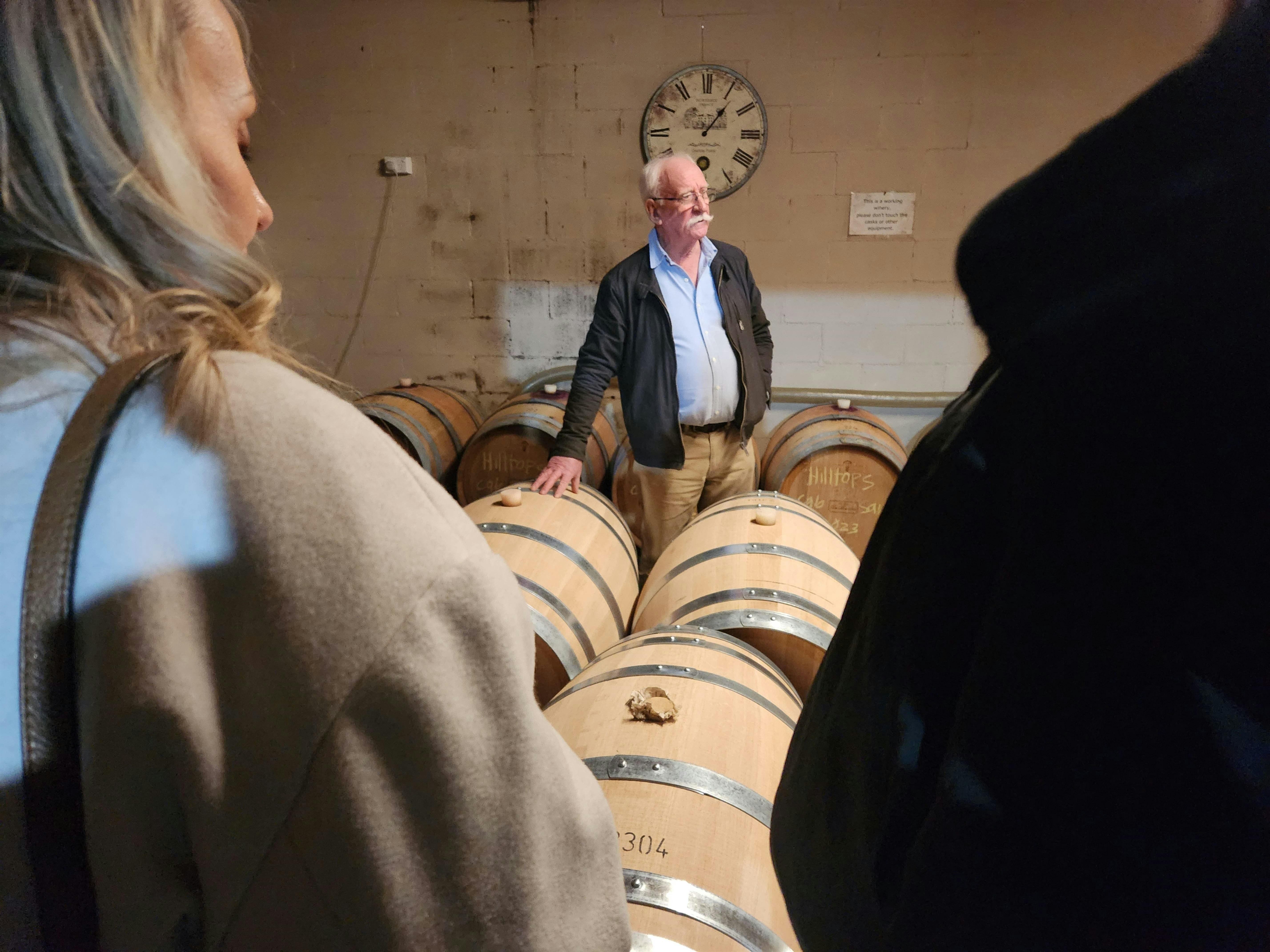 A vintner standing in front of oak barrels