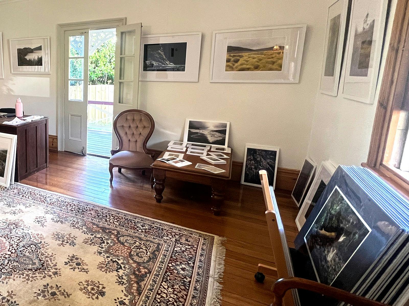 Interior of studio gallery in heritage home with artwork, antique furniture and floor rug on timber