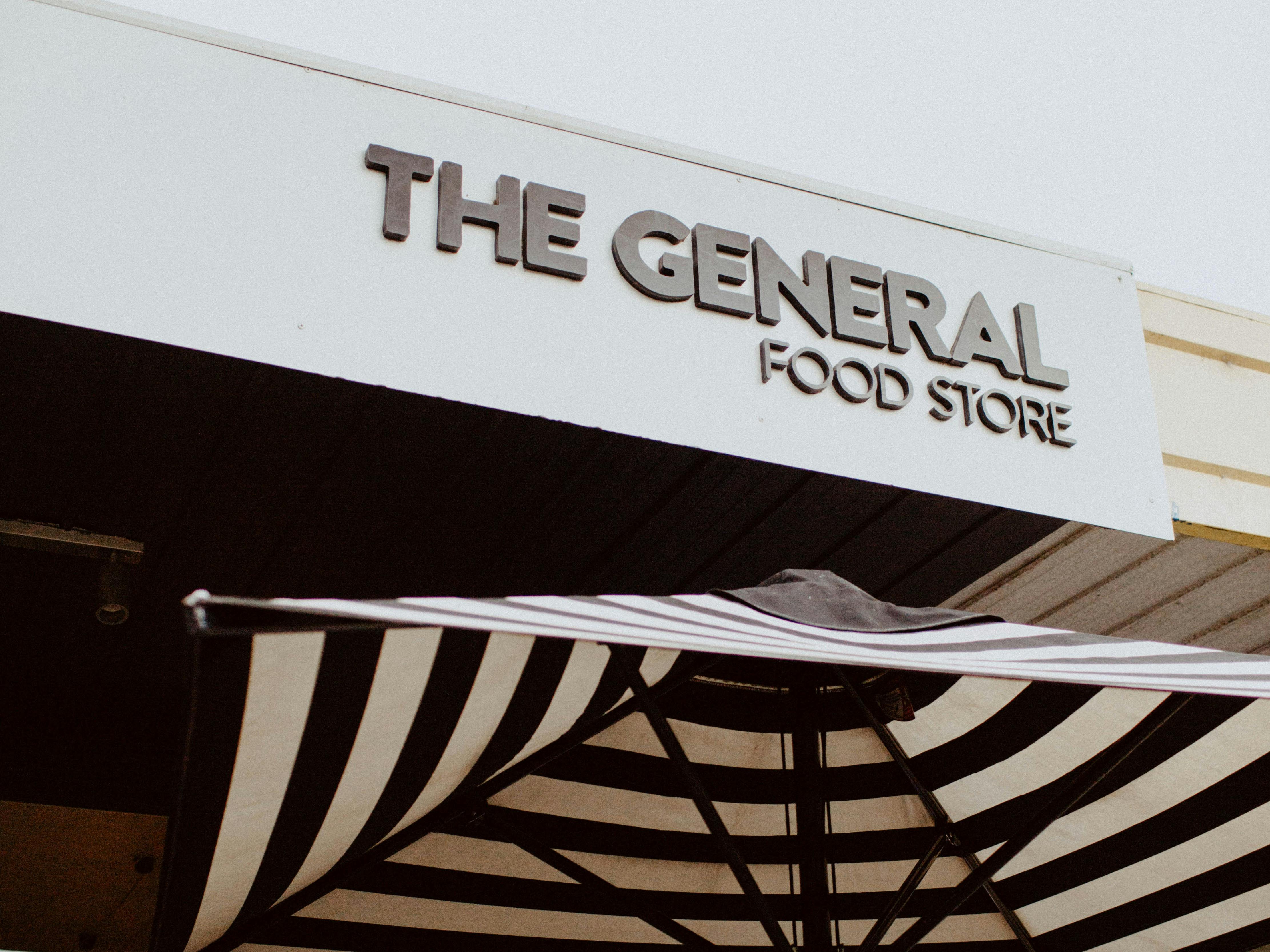 Image of facade signage and umbrella outside The General Food Store