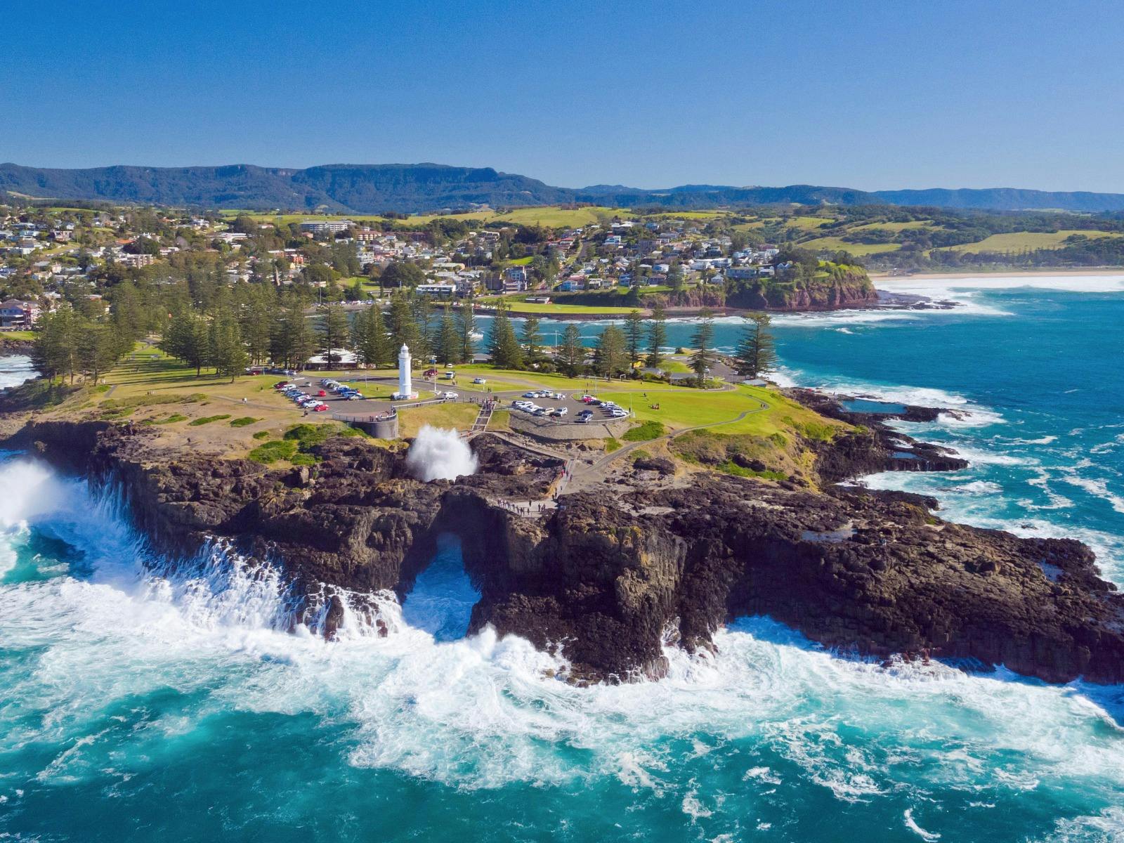 aerial immage of kiama blowhole spraying with lighthouse in background