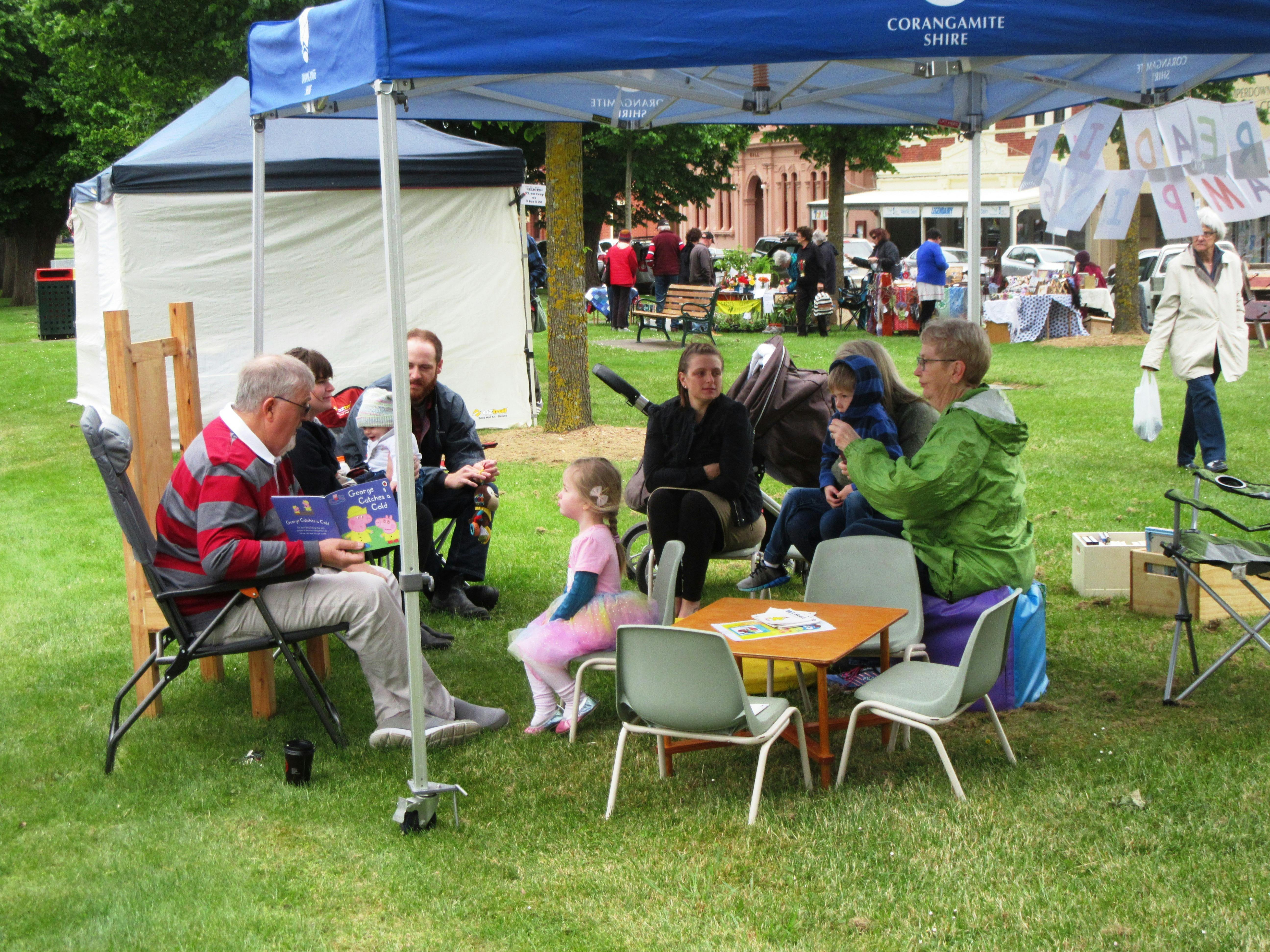 Group sitting under a gazebo reading to children