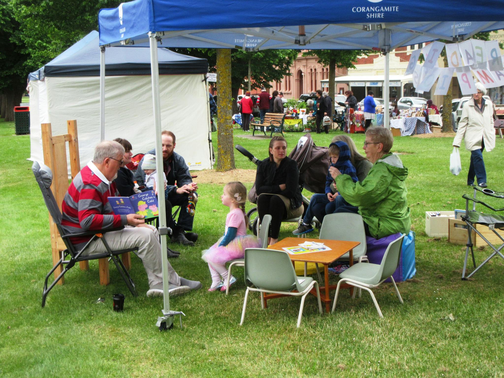 Group sitting under a gazebo reading to children