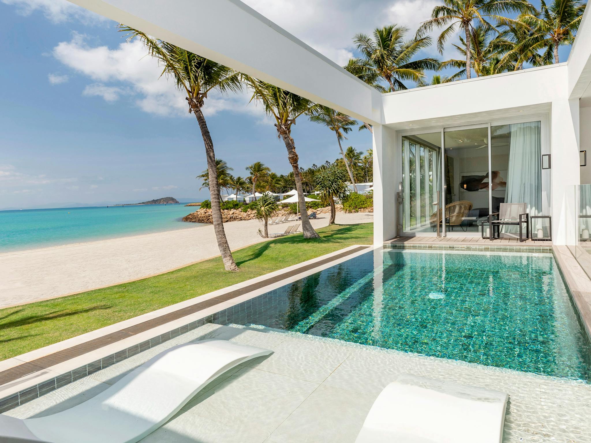A beach house with a private pool, white modern design, palm trees, and ocean views nearby. A beach house with a private pool, white modern design, palm trees, and ocean views nearby.