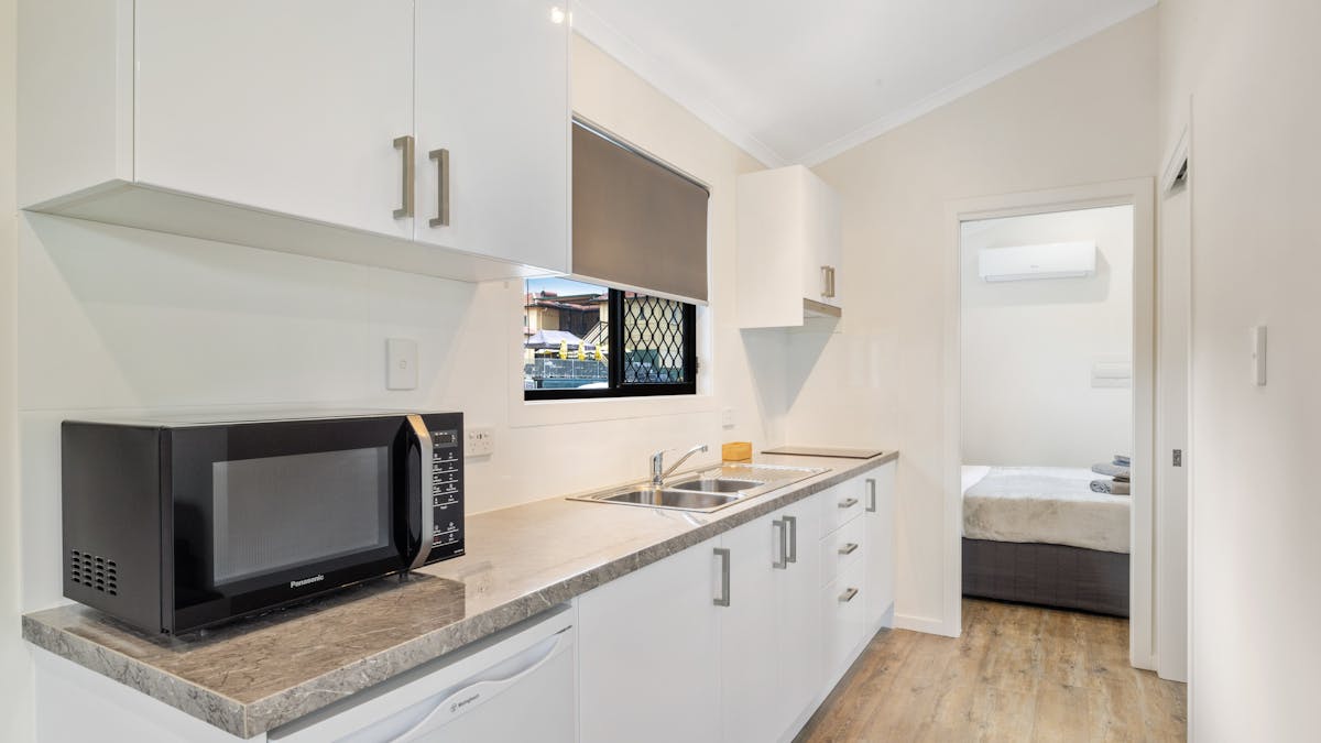 Two bedroom kitchen includes microwave, sink and two base cooktop.