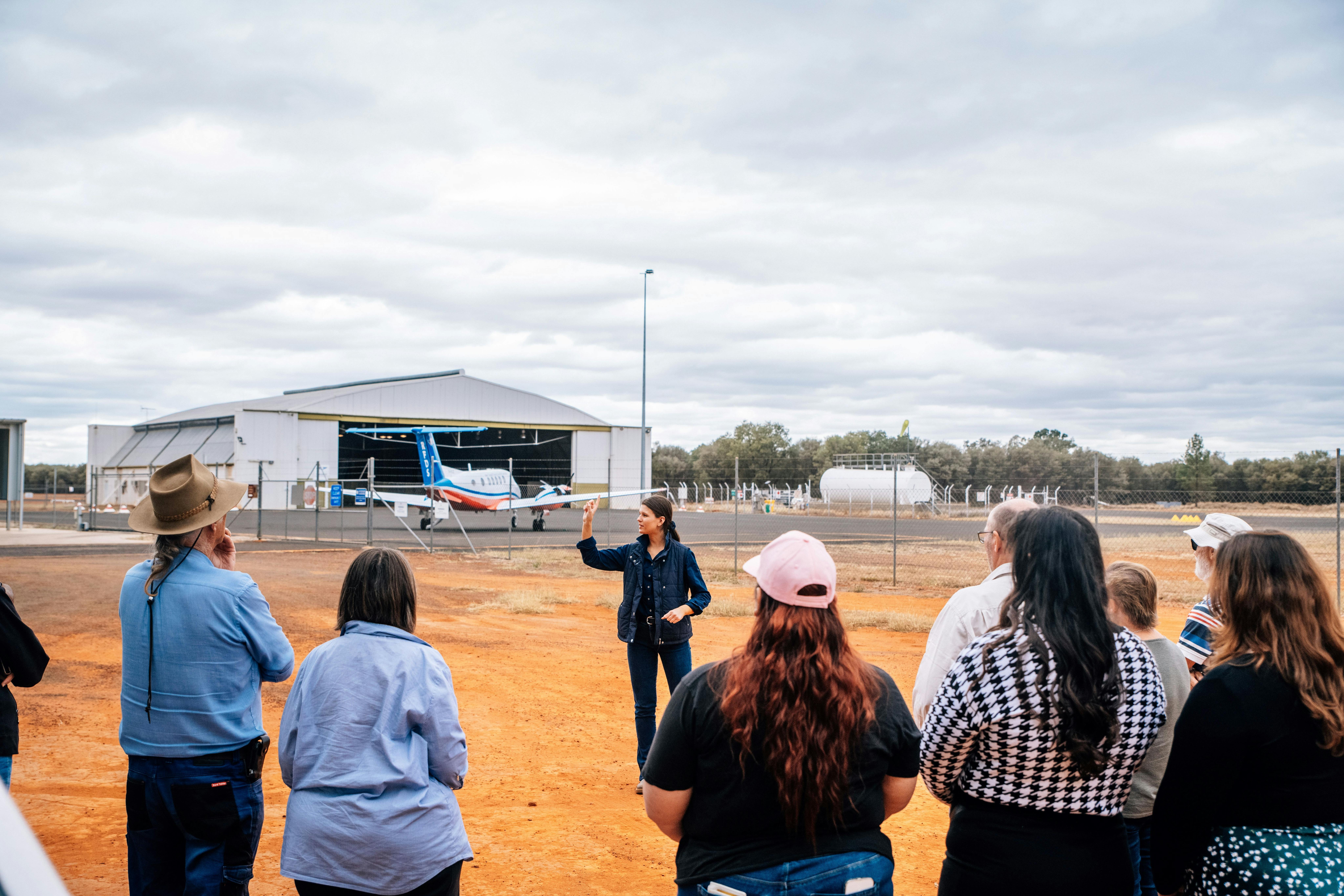 tour guide speaking to guests outside on the tour with the RFDS plane at the WWII hangar